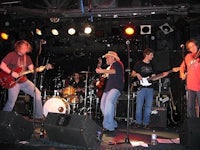 a group of people on stage with guitars and drums