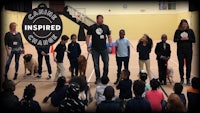 a group of children are standing in a gym with a dog