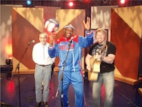 three men standing on a stage with a ball in their hands