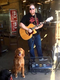 a man playing an acoustic guitar next to a dog