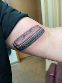 a tattoo of a harmonica on a person's arm