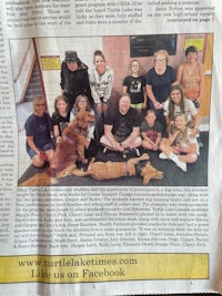 a newspaper article with a group of people posing with dogs