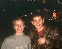two men standing next to each other at a party