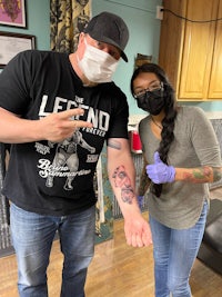 a man and woman posing for a photo in a tattoo shop